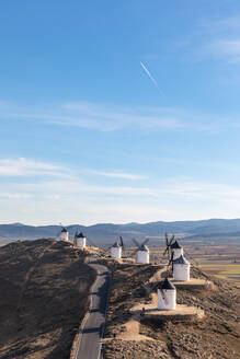 Spanien, Provinz Toledo, Consuegra, Landstraße entlang einer Reihe von alten Windmühlen auf einem Hügel - WPEF02131