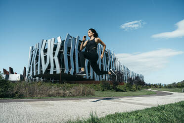 Young female jogger on a way in front of a modern building - MTBF00043