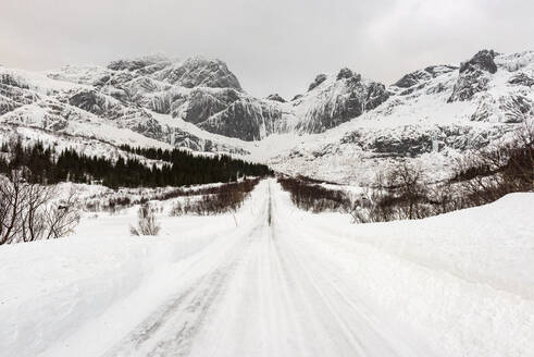 Schneebedeckte Straße unter arktischen Winterbedingungen, Lofoten, Nordland, Arktis, Norwegen, Europa - RHPLF12612