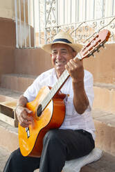 Local man singing and playing his guitar in the Plaza Mayor of Trinidad, Cuba, West Indies, Caribbean, Central America - RHPLF12633