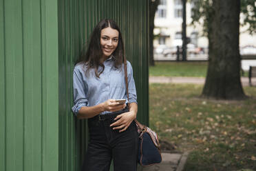 Young traveller leaning on green wall at station - VPIF01722