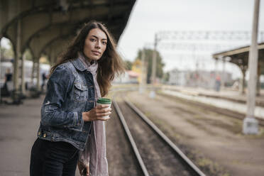 Junge weibliche Reisende mit Kaffee zum Mitnehmen am Bahnhof - VPIF01740