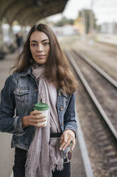 Junge weibliche Reisende mit Kaffee zum Mitnehmen am Bahnhof - VPIF01741