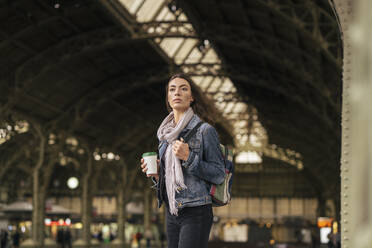 Junge weibliche Reisende mit Kaffee zum Mitnehmen auf dem Bahnsteig - VPIF01745