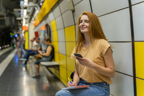 Frau benutzt Smartphone in U-Bahn-Station, lizenzfreies Stockfoto