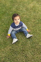 Portrait of little boy sitting on lawn - VGF00318