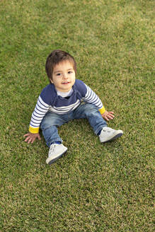 Porträt eines kleinen Jungen auf dem Rasen sitzend - VGF00318
