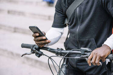 Nahaufnahme eines Mannes mit Fahrrad und Smartphone - CJMF00155