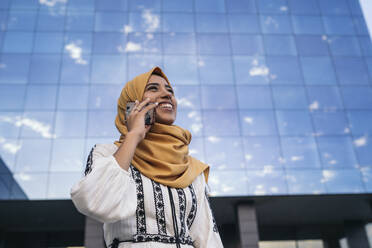 Junge muslimische Frau trägt gelben Hijab und benutzt ein Smartphone - MPPF00233