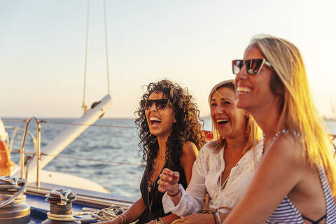 Freunde lachen während einer Bootsfahrt im Abendlicht, lizenzfreies Stockfoto