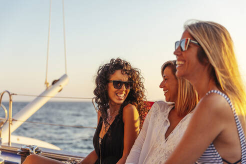 Friends laughing during boat trip in the evening light - MOSF00113