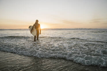 Surfer mit Surfbrett im Meer bei Sonnenuntergang - AHSF01053