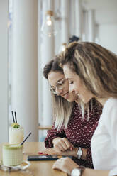 Friends in a cafe looking at a smartphone - MOMF00772