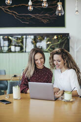 Freunde benutzen Laptop in einem Cafe - MOMF00775