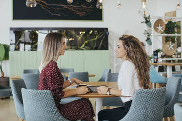 Friends having a coffee and talking in a cafe - MOMF00778