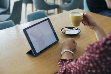 Woman having coffee and looking at computer tablet - MOMF00790