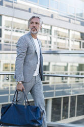 Fashionable mature businessman with travelling bag on the go - DIGF08556