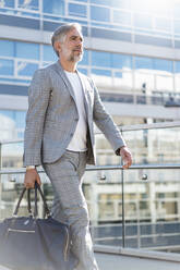 Fashionable mature businessman with travelling bag on the go - DIGF08566