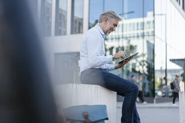 Smiling mature businessman using tablet in the city - DIGF08585