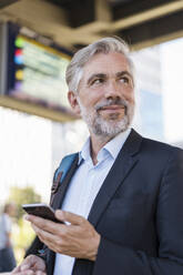 Portrait of mature businessman with cell phone at the station - DIGF08597
