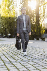 Fashionable mature businessman with bag on the go in the city - DIGF08604