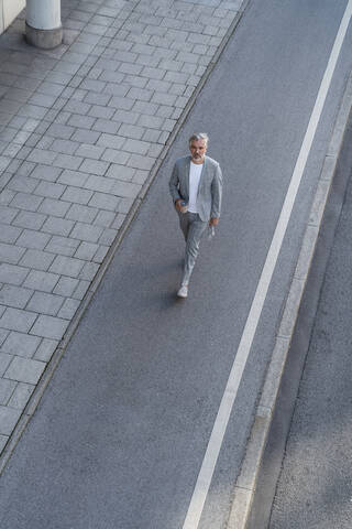 Draufsicht auf einen reifen Geschäftsmann, der auf einer Straße geht, lizenzfreies Stockfoto