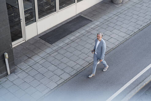 Draufsicht auf einen reifen Geschäftsmann, der auf einer Straße geht - DIGF08634