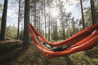 Young woman lying in hammock in forest - JOHF04414