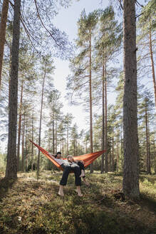 Junges Paar liegt in Hängematte im Wald - JOHF04416