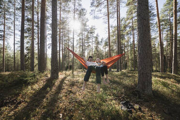 Young couple lying in hammock in forest - JOHF04450