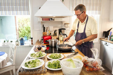 Älterer Mann bei der Zubereitung einer Mahlzeit in der Küche - JOHF04455