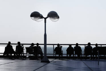 Silhouette von Menschen, die sich am Meer entspannen - JOHF04466