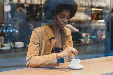 Junge Frau mit Afrofrisur trinkt Kaffee in einem Cafe - CUF52564