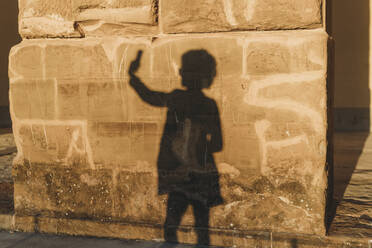 Schatten einer Frau, die ein Selfie auf einer Steinmauer macht - CUF52568