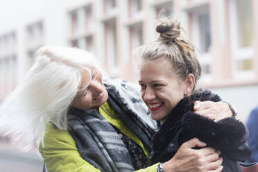 Mature woman and daughter hugging on city street - CUF52577