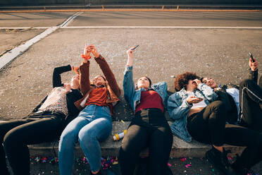 Friends together on kerb taking selfie and using smartphones, Milan, Italy - CUF52581