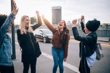 Freunde erheben die Arme im Triumph auf der Straße, Mailand, Italien - CUF52593