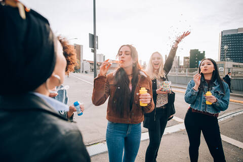 Freunde feiern mit Konfetti und Seifenblasen auf der Straße, Mailand, Italien, lizenzfreies Stockfoto