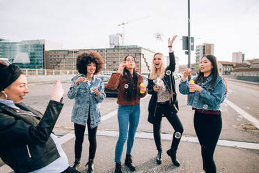 Friends celebrating with confetti and soap bubbles in street, Milan, Italy - CUF52616