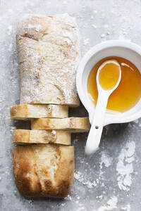 Stilleben eines bemehlten und nicht bemehlten Ciabatta-Brotes auf einem Backblech mit Schüssel und Löffel, Draufsicht - CUF52632