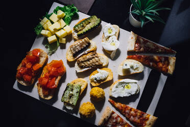 Shared platter with pizza, bruschetta and cheese on cafe table, overhead view - CUF52656