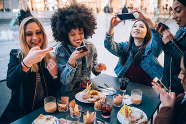 Freunde fotografieren ihr Essen und ihre Getränke in einem Straßencafé, Mailand, Italien - CUF52707