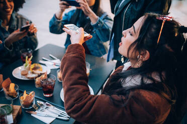 Freunde fotografieren ihr Essen und ihre Getränke in einem Straßencafé, Mailand, Italien - CUF52708