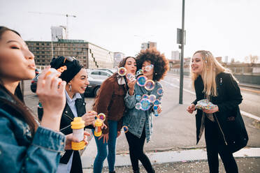 Friends celebrating with confetti and soap bubbles in street, Milan, Italy - CUF52732