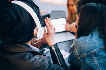 Friends working on virtual reality project at outdoor cafe, Milan, Italy - CUF52756