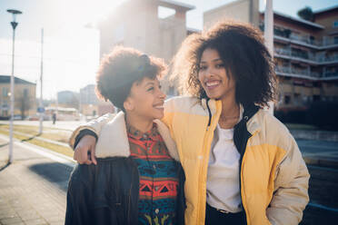 Two cool young female friends on sunlit urban sidewalk, portrait - CUF52788