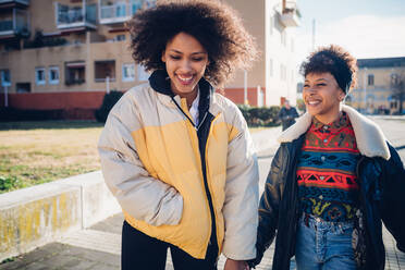 Two young female friends strolling on urban sidewalk - CUF52790