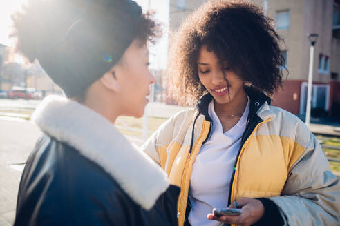 Zwei coole junge Freundinnen schauen in der Stadt auf ihr Smartphone - CUF52804