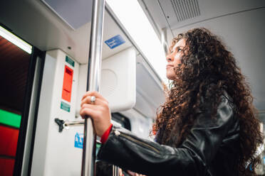 Mittlere erwachsene Frau mit langen lockigen Haaren in der U-Bahn - CUF52826