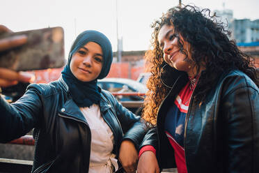 Junge Frau im Hidschab und Freundin posieren für ein Selfie in der Stadt - CUF52837
